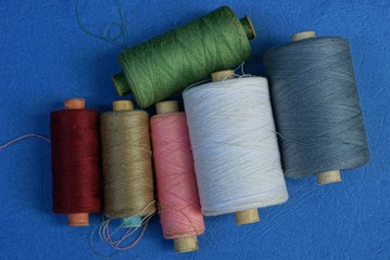 spools of colored thread lie on a blue table