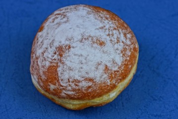 one brown donut with white powder does not lie on a blue table