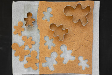 Homemade raw dough for cooking Christmas cookies on a black background, top view. Flat lay, overhead, from above. Closeup.