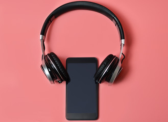 Headphones and smartphone on a pink background