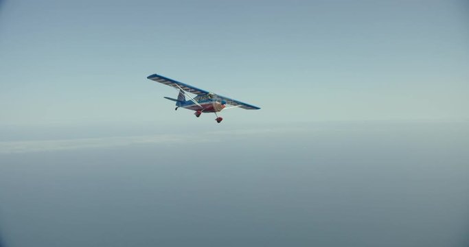 Foggy helicopter aerial of small seaplane flying above ocean, day