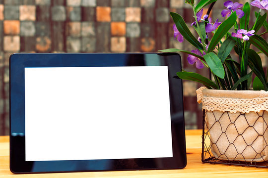 Mockup image of black tablet pc with blank white screen and flowers pot 