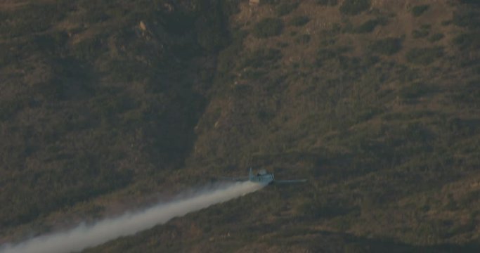 Helicopter aerial shot following skywriting plane over mountains, overcast day