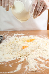 A baker pouring a sour cream into a pile of flour. Making Pastry Dough for Hungarian Cake. Series.