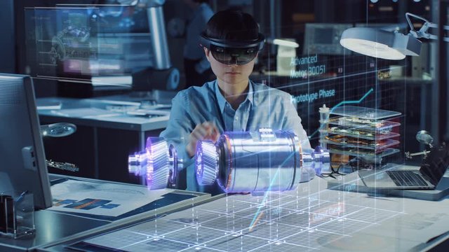 Industrial Factory Chief Engineer Wearing AR Headset Designs a Prototype of an Electric Motor on the Holographic Projection Blueprint. Futuristic Virtual Design of Mixed Technology Application.