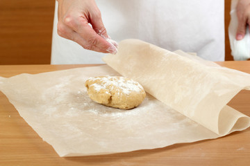 A baker rolling a dough between sheets of baking paper. Making Pastry Dough for Hungarian Cake. Series.