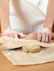 A baker rolling a dough between sheets of baking paper. Making Pastry Dough for Hungarian Cake. Series.