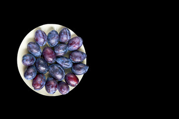 plum on a plate on a black background isolate