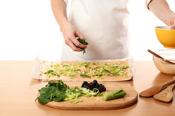 Spreading sliced spinach on dough. Making Pizza with Leek and Spinach. Series.
