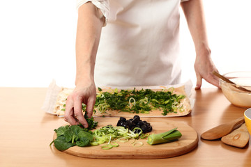 Spreading sliced spinach on dough. Making Pizza with Leek and Spinach. Series.