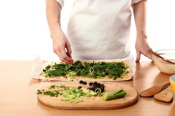 Spreading sliced olives on dough. Making Pizza with Leek and Spinach. Series.