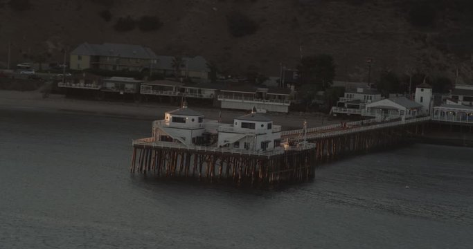 Sunsetting over white building at edge of pier, helicopter aerial