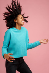 Portrait of excited african american young woman with bright smile dressed in casual clothes dance with invisible guitar over pink background.