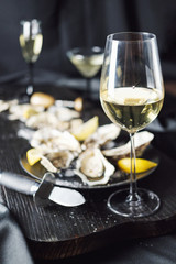White wine with oysters on a dark background