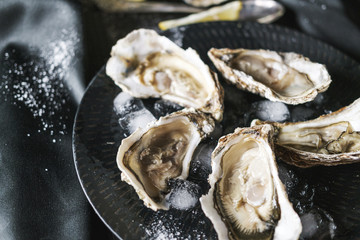 Open oysters with lemon in a black plate
