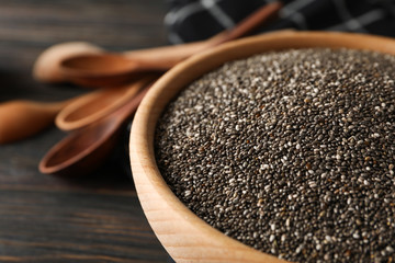 Chia in wooden bowl on wood background, close up