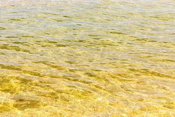 Texture of the surface of the water in the sea lit by the morning sun