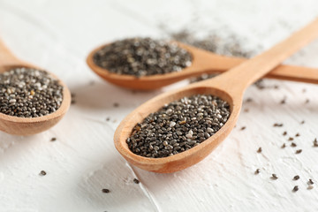 Wooden spoons and chia on white background, close up