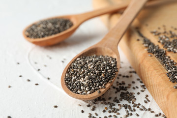 Wooden spoons with chia and board on white background, close up
