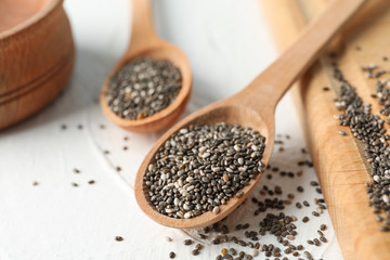 Wooden spoons with chia and board on white background, close up