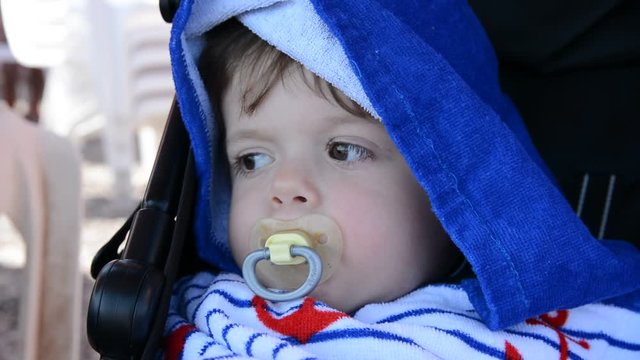 little child with pacifier in a towel with a hood