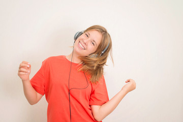 Happy teenager girl in headphones dancing and listening to music.