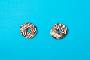 Naklejka premium Two white donuts with eyes and chocolate decoration with nuts against blue background. View from above.