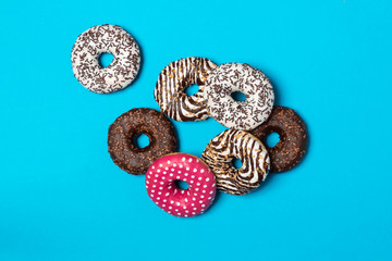 Colorful donuts with icing on blue background.White hut is aside, Top view with copy space, realistic style.