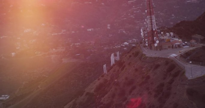 Helicopter aerial shot rotating around cellphone tower on Hollywood Hills, sunset