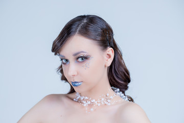 Portrait of a beautiful attractive girl with fantasy make up and hair style isolated on white background, series of photos.blue lips, elegant necklace, design hair. Conceptual art. Snow Queen.