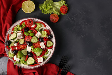 Healthy Greek salad of green lettuce, cherry tomato, onion, pepper, feta cheese, black olives, basil, cucumbers, with olive oil and lemon juice, Closeup, horizontal orientation