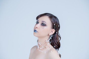 Portrait of a beautiful attractive girl with fantasy make up and hair style isolated on white background, series of photos.blue lips, elegant necklace, design hair. Conceptual art. Snow Queen.