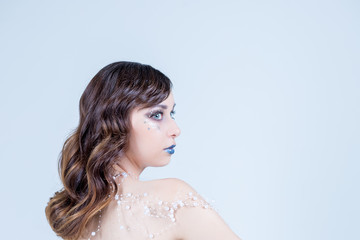 Young woman in creative image with silver artistic make-up.Winter, Christmas Girl Make up. Holiday Make-up with gems. Snow Queen High Fashion Portrait. Eyeshadows, False Eyelashes and Crystals