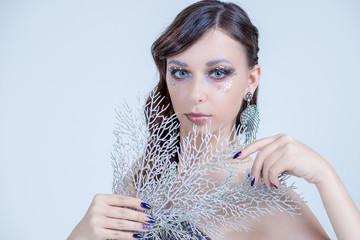 Young woman in creative image with silver artistic make-up.Winter, Christmas Girl Make up. Holiday Make-up with gems. Snow Queen High Fashion Portrait. Eyeshadows, False Eyelashes and Crystals
