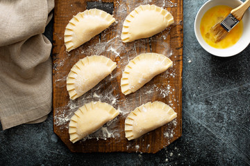 Hand pies or pierogies with potato filling raw on a board ready to be baked © fahrwasser
