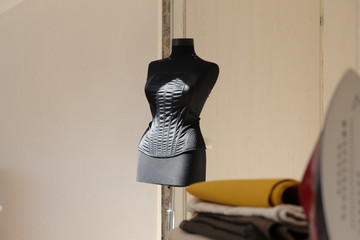 black dressmaker mannequin, textile fabrics and clothes iron inside a white 