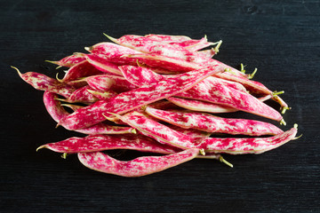 Pink spotty bean pods (Phaseolus) on a wooden black table. Harvest season