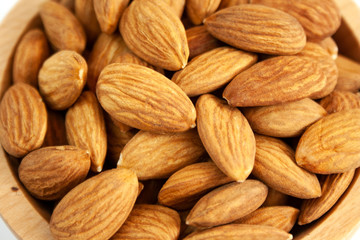 Almonds in a wood bowl on white background