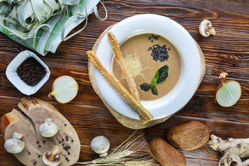 Mushroom soup with pasta with champignons and herbs on a brown wooden background