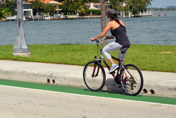 Woman riding a bicycle across the Venetia Causeway in Miami Beach,Florida with RivoAlto island in the background
