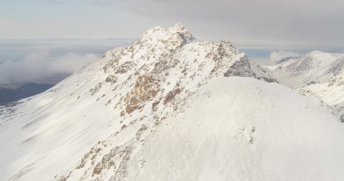 Aerial helicopter shot, fly up to bright white Alaskan mountain peak, drone footage