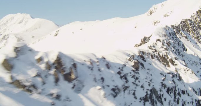 Aerial helicopter shot, track across snowy mountainside, drone footage
