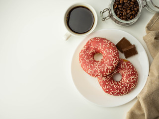 Pączki z różową polewą, kawa w filiżance. Widok z góry.