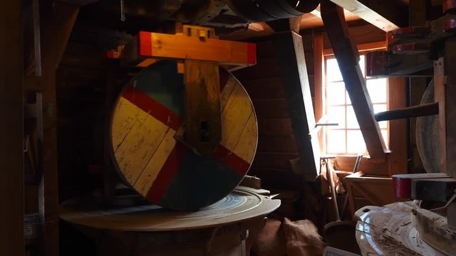 Zaandam Zaanse Schans near Amsterdan inside a typical dutch windmill close up of large wooden wheels grinding peanuts. Slow motion