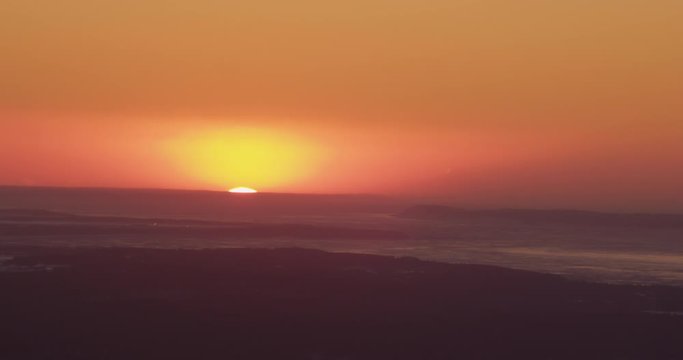 Aerial helicopter shot, wide view of sunset on the ocean over Alaskan peninsulas and rivers, drone footage