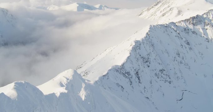Aerial helicopter shot, track down from snowy mountain peak, drone footage