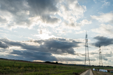 Strommasten unter dunklem Wolkenhimmel