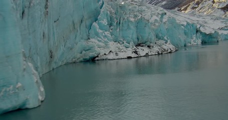  Aerial helicopter closeup details up and over glacial ice in mountain lake at golden hour, lens flare, drone footage