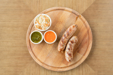 Grilled sausages. Serving on a wooden Board. Barbecue restaurant menu, a series of photos of different meats. Pickled cabbage and two sauces