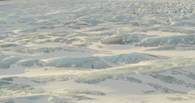  Aerial helicopter shot, slow track on the details of a rippling glacier at golden hour, drone footage